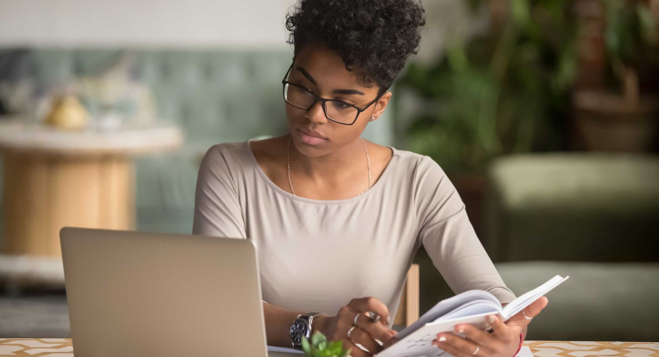 Woman doing research on her laptop and taking notes