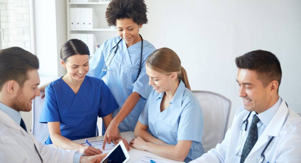 A group of doctors sitting at a table talking, smiling and laughing