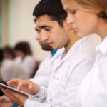 People wearing white coats using an ipad