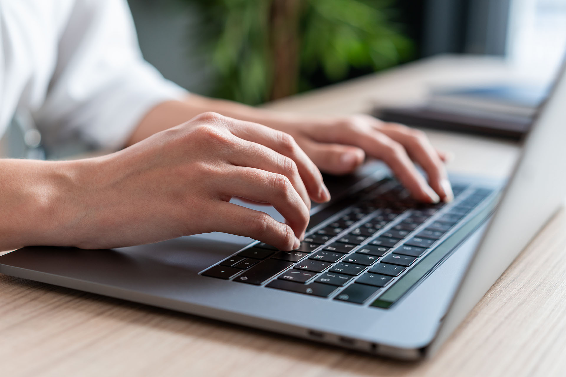 Someone typing on a laptop, with a focus on the hands and keyboards