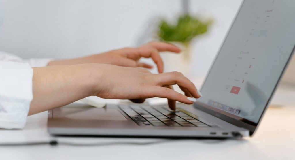 womans hands typing on laptop